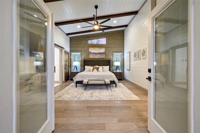 bedroom with beam ceiling, wooden walls, high vaulted ceiling, and wood finished floors