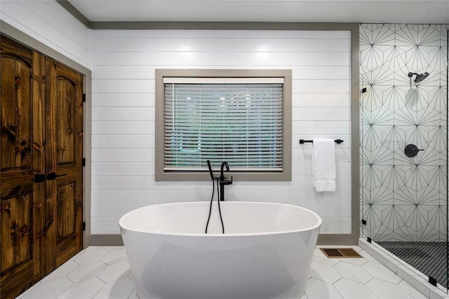 full bath featuring a shower stall, a soaking tub, and tile patterned floors