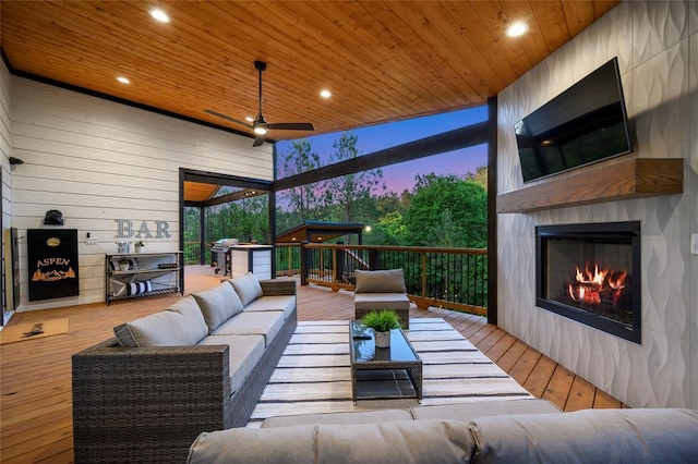 deck featuring an outbuilding, an outdoor living space with a fireplace, area for grilling, and ceiling fan