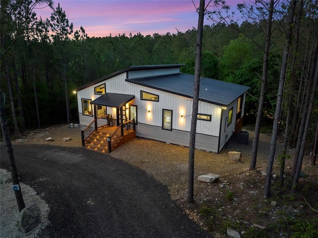 modern farmhouse style home featuring a forest view and metal roof