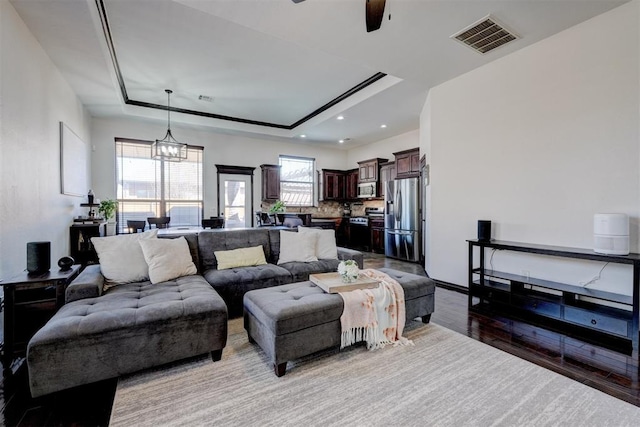 living area with recessed lighting, visible vents, light wood-style flooring, and a raised ceiling