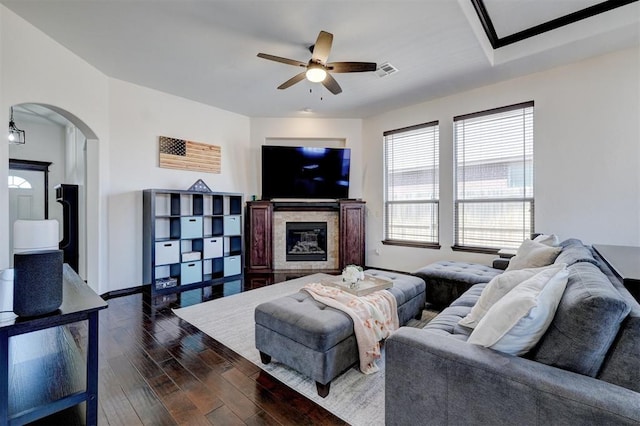 living area with visible vents, baseboards, arched walkways, hardwood / wood-style flooring, and a glass covered fireplace