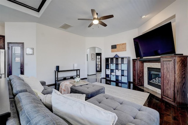 living room featuring visible vents, wood finished floors, a glass covered fireplace, arched walkways, and ceiling fan