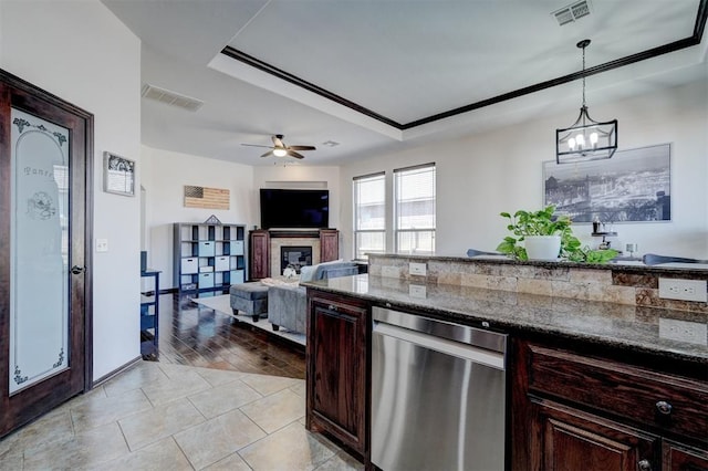 kitchen with dark stone countertops, visible vents, pendant lighting, and a glass covered fireplace