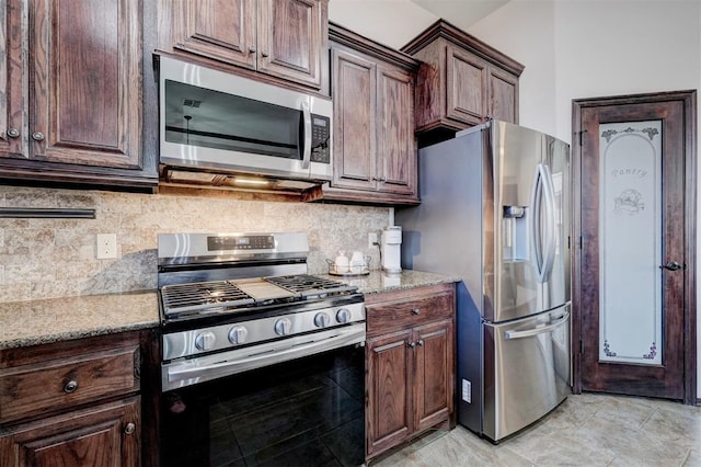 kitchen featuring decorative backsplash, dark brown cabinetry, light stone countertops, and stainless steel appliances