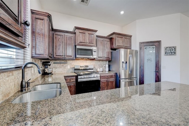 kitchen with visible vents, a sink, light stone counters, tasteful backsplash, and appliances with stainless steel finishes