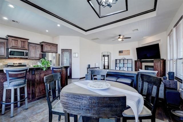 dining area with recessed lighting, visible vents, arched walkways, and a glass covered fireplace