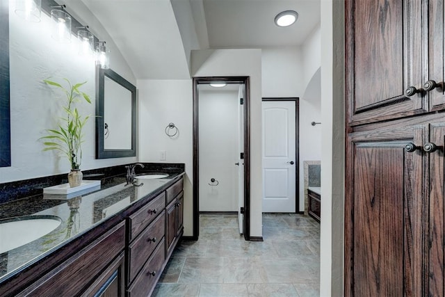 bathroom with double vanity, a bath, and a sink