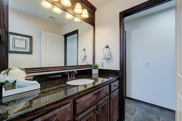 bathroom with vanity, stone finish floor, baseboards, and visible vents