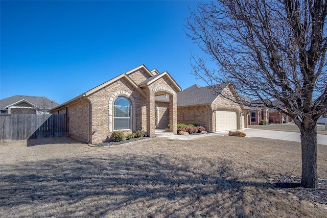 view of front of home with concrete driveway, an attached garage, fence, and brick siding