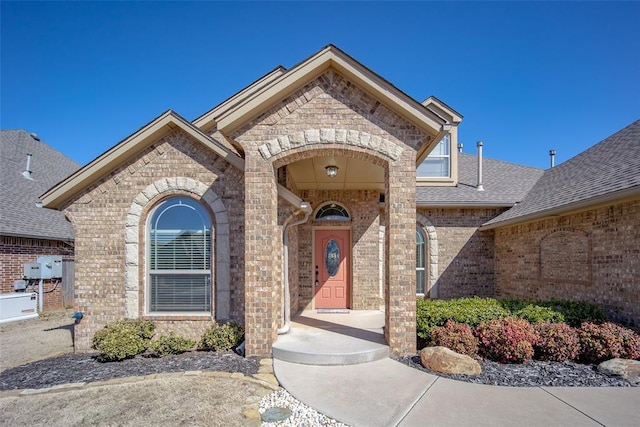 property entrance with brick siding and roof with shingles