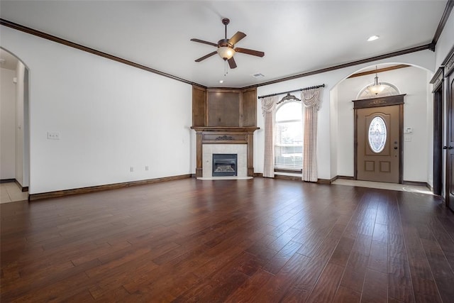 unfurnished living room featuring wood finished floors, arched walkways, ceiling fan, and a fireplace