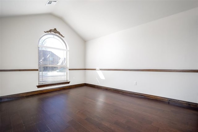 spare room with lofted ceiling, wood finished floors, visible vents, and baseboards