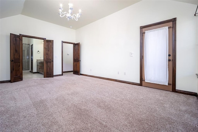 unfurnished bedroom featuring light carpet, lofted ceiling, connected bathroom, baseboards, and a chandelier