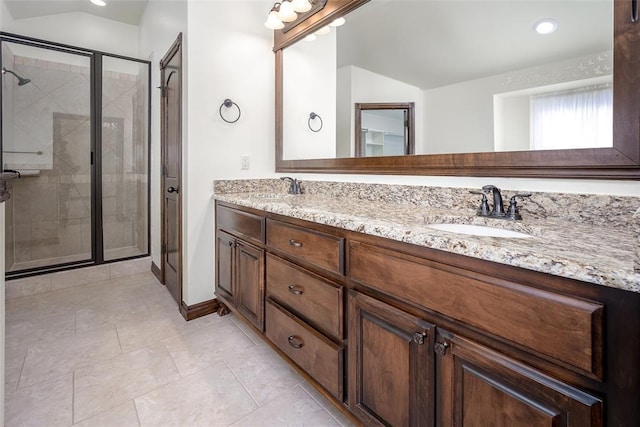 bathroom with double vanity, vaulted ceiling, a shower stall, and a sink