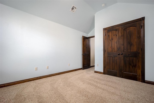 unfurnished bedroom featuring visible vents, carpet floors, baseboards, and vaulted ceiling