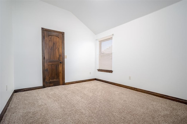 carpeted spare room with baseboards and lofted ceiling