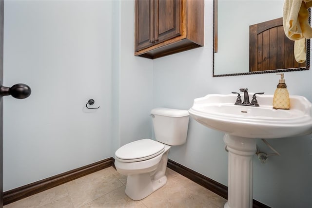 half bath featuring baseboards, toilet, and tile patterned flooring