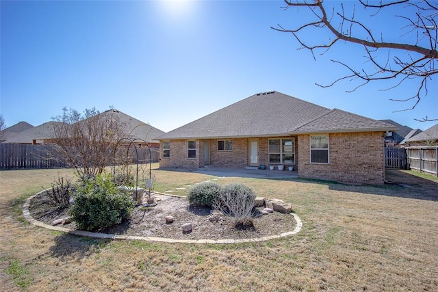 back of house featuring brick siding, a patio, fence, and a lawn