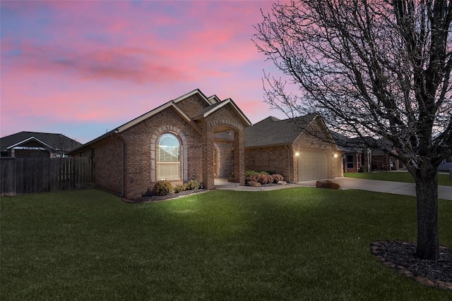view of front of home featuring brick siding, an attached garage, a front lawn, fence, and driveway