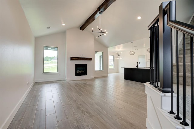 8101 Jenny Ln, Edmond, OK 73034 - unfurnished living room with a chandelier, beam ceiling, baseboards, stairs, and light wood-style flooring