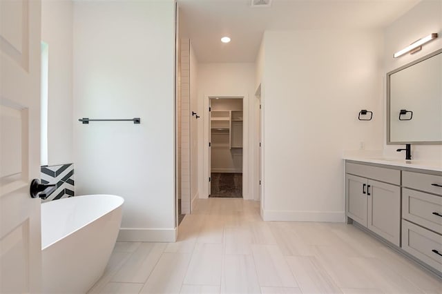 8101 Jenny Ln, Edmond, OK 73034 - full bathroom featuring baseboards, a spacious closet, a freestanding bath, vanity, and recessed lighting