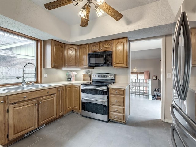 kitchen featuring a sink, ceiling fan, light countertops, stainless steel appliances, and brown cabinets