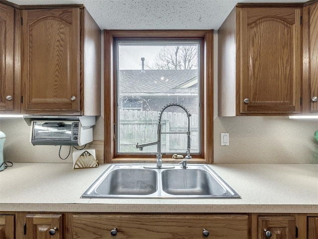 kitchen featuring a sink, brown cabinetry, and light countertops