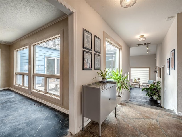 hall with baseboards, visible vents, and a textured ceiling