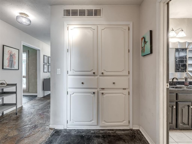 corridor with visible vents, baseboards, and a sink