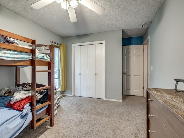 bedroom with carpet, baseboards, ceiling fan, a closet, and a textured ceiling