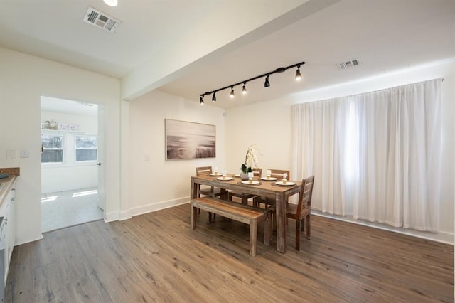 dining area featuring track lighting, wood finished floors, visible vents, and baseboards