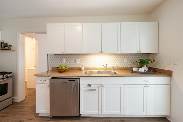 kitchen with wood finished floors, a sink, decorative backsplash, stainless steel appliances, and white cabinetry