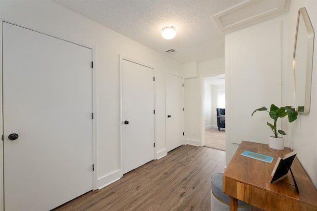 interior space featuring visible vents, light wood-style floors, attic access, and a textured ceiling