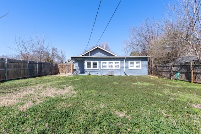 rear view of property featuring central AC unit, a yard, and a fenced backyard