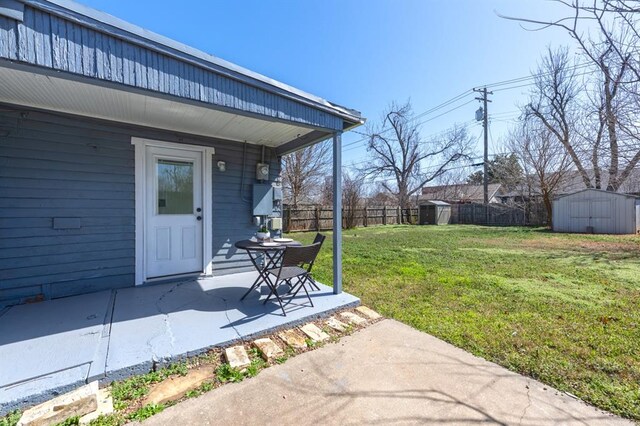 view of yard with an outbuilding, a storage shed, a patio, and fence