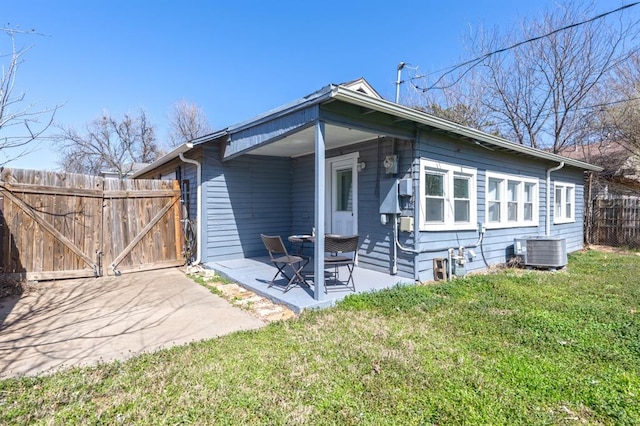 back of house featuring fence, cooling unit, a yard, a patio, and a gate