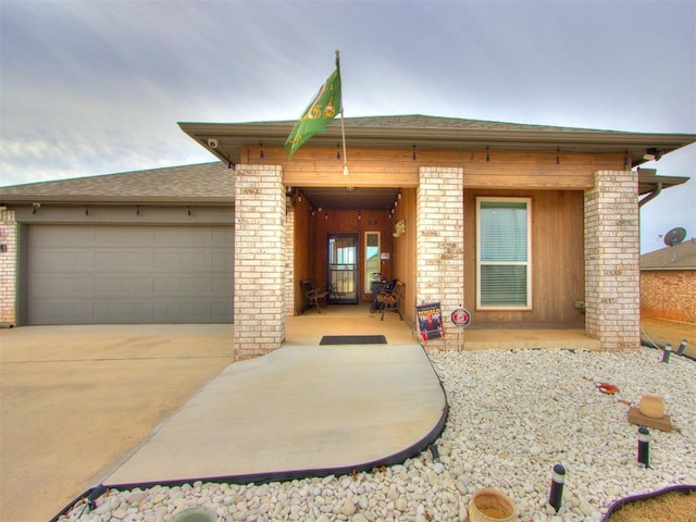 view of front of home with concrete driveway, an attached garage, and a shingled roof