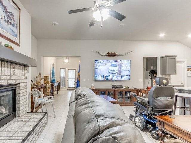 living area featuring lofted ceiling, a fireplace, and ceiling fan