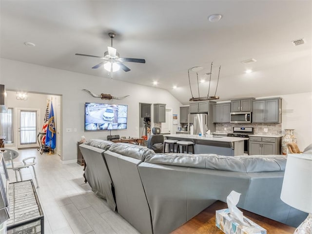 living room featuring a ceiling fan, visible vents, recessed lighting, vaulted ceiling, and light wood-style floors