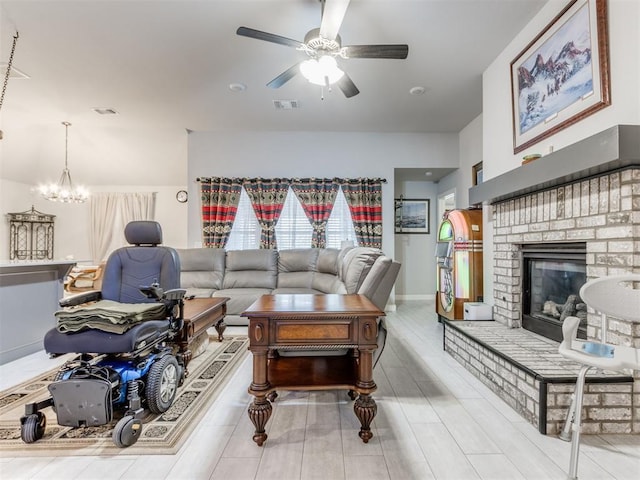 living area with visible vents, baseboards, a fireplace, and ceiling fan with notable chandelier