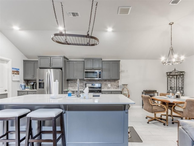 kitchen with decorative backsplash, gray cabinets, visible vents, and stainless steel appliances