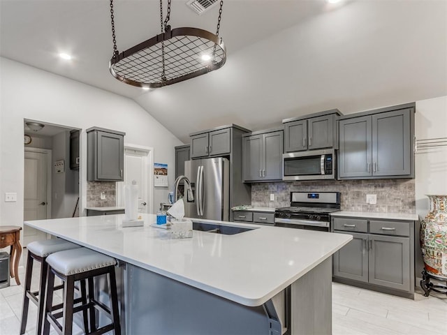 kitchen with stainless steel appliances, lofted ceiling, a breakfast bar, and light countertops