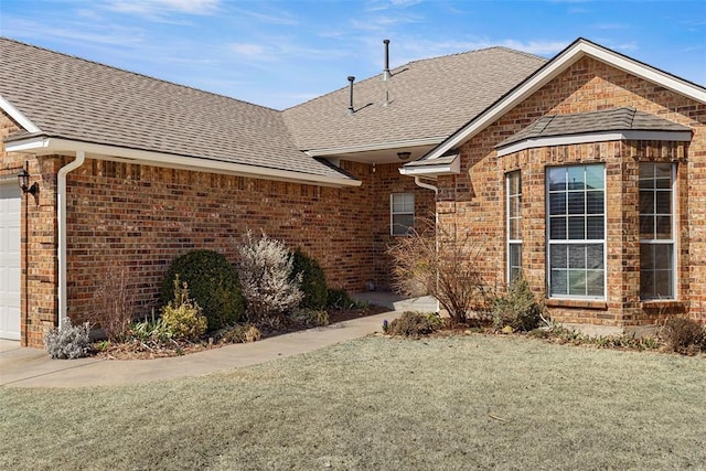 ranch-style house with brick siding, an attached garage, and a shingled roof