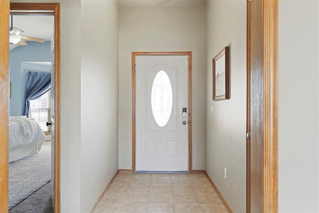 foyer with light tile patterned floors, baseboards, and a ceiling fan