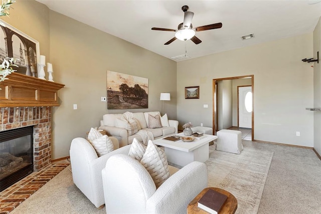 living room featuring visible vents, a brick fireplace, baseboards, and a ceiling fan