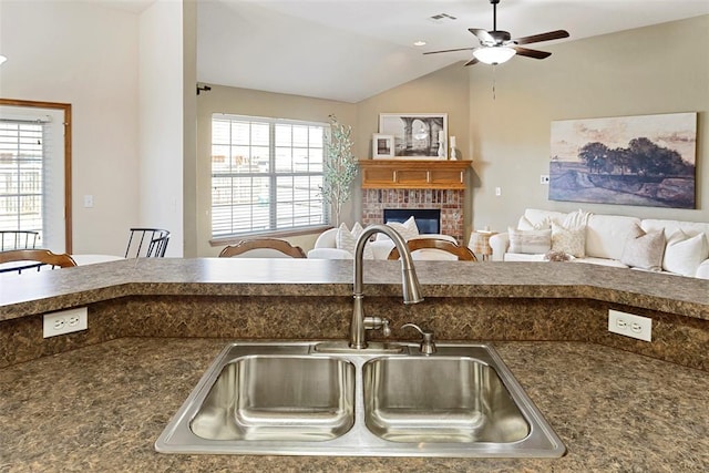 kitchen featuring a ceiling fan, visible vents, a fireplace, a sink, and open floor plan