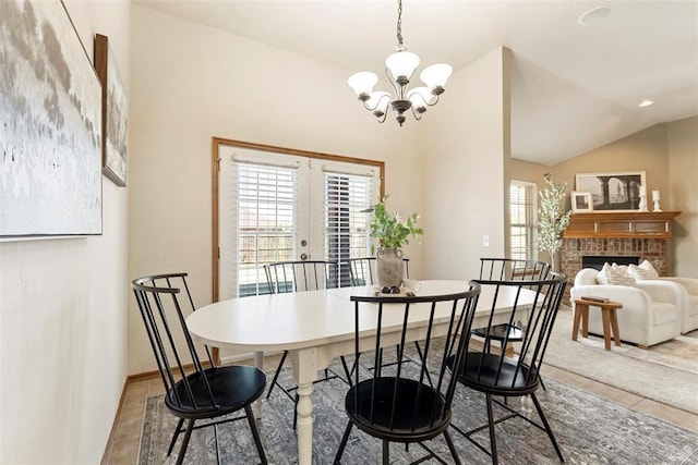 dining room with baseboards, vaulted ceiling, a fireplace, french doors, and a notable chandelier