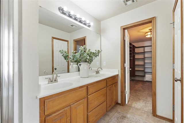 bathroom with tile patterned flooring, double vanity, visible vents, and a sink