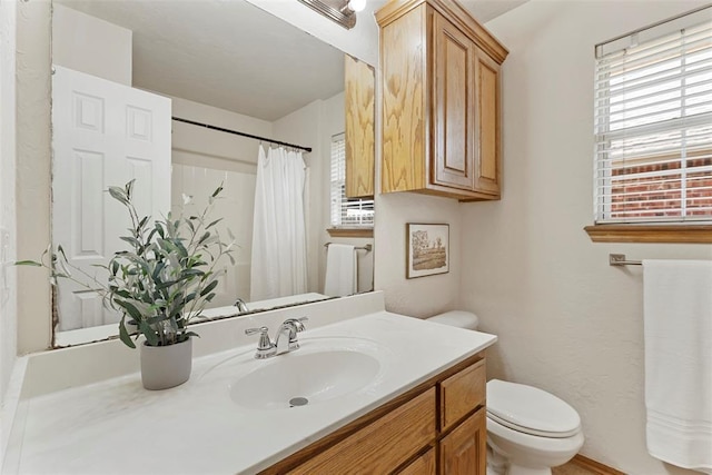 full bath featuring vanity, toilet, and a healthy amount of sunlight